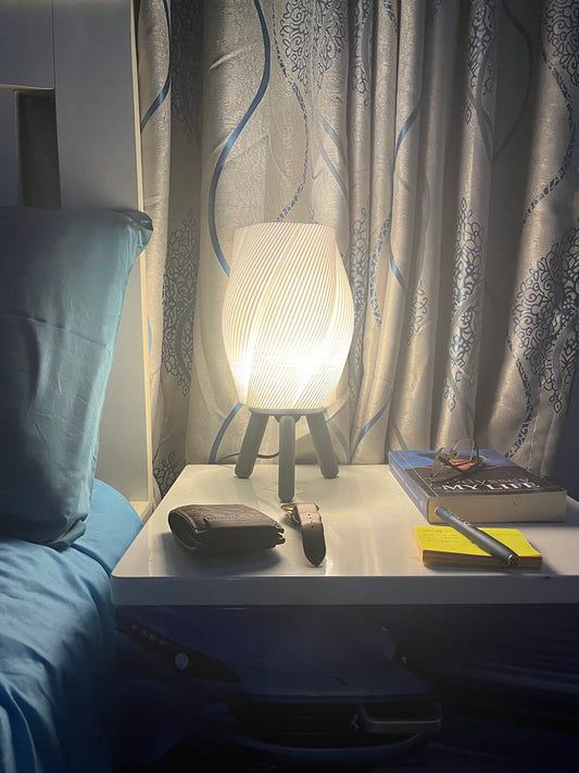 3D printed grey Taifū bedside/table lamp on a bedside table