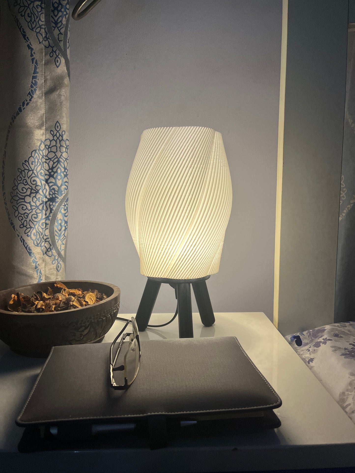 3D printed black Taifū bedside/table lamp on a bedside table